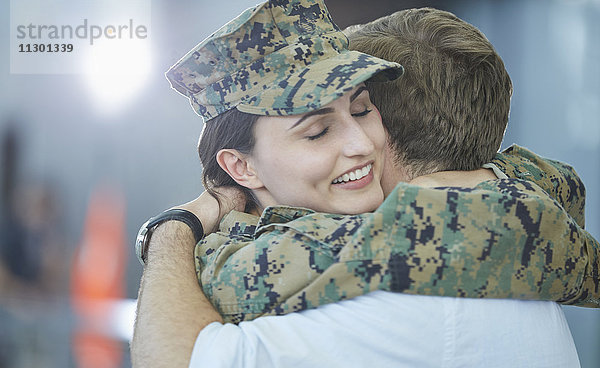Mann begrüßt umarmende Soldatenfrau