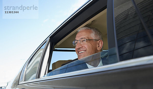 Lächelnder Geschäftsmann schaut aus dem Stadtautofenster