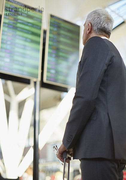 Geschäftsmann bei der Ankunft am Flughafen  Abfahrtstafel