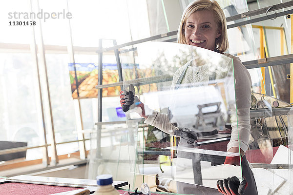 Portrait lächelnder Glasmaler beim Heben von Glas im Atelier