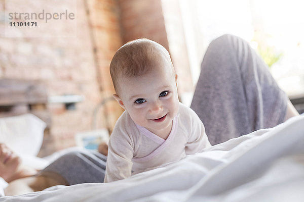 Portrait lächelndes Mädchen auf dem Bett liegend mit Mutter