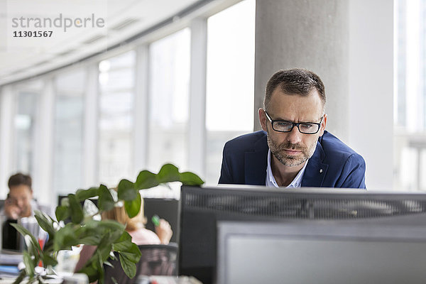 Seriöser Geschäftsmann  der am Computer im Büro arbeitet.