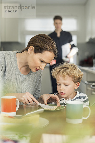 Frau beim Frühstücken im Wohnzimmer zu Hause