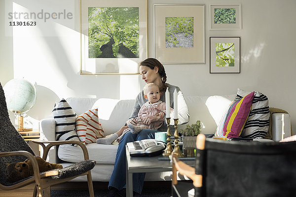 Frau sitzend mit Mädchen auf dem Sofa zu Hause