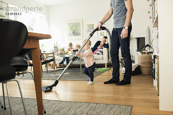 Niedriger Bereich von Mensch und Kleinkind Reinigung Boden mit Staubsauger zu Hause