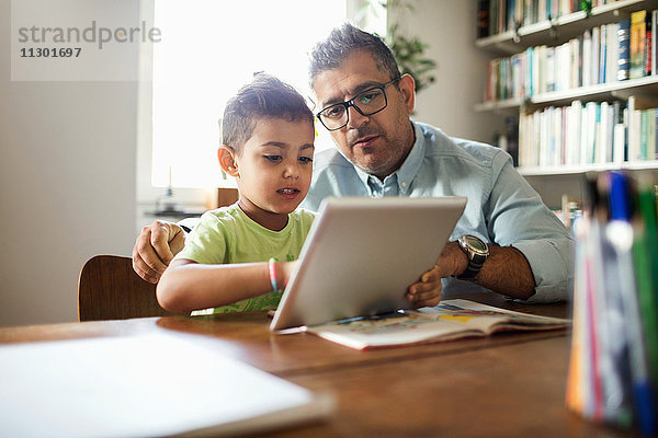 Vater und Sohn beim Lernen am Tisch mit dem digitalen Tablett