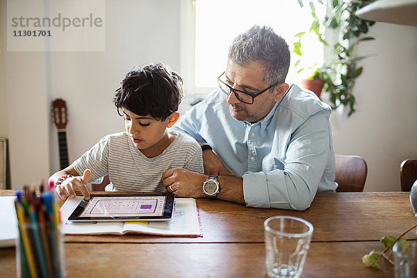 Vater unterstützt den Sohn bei der Verwendung des digitalen Tabletts zu Hause