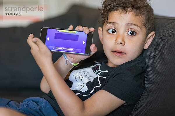 Junge zeigt Spiel auf dem Smartphone-Bildschirm zu Hause an