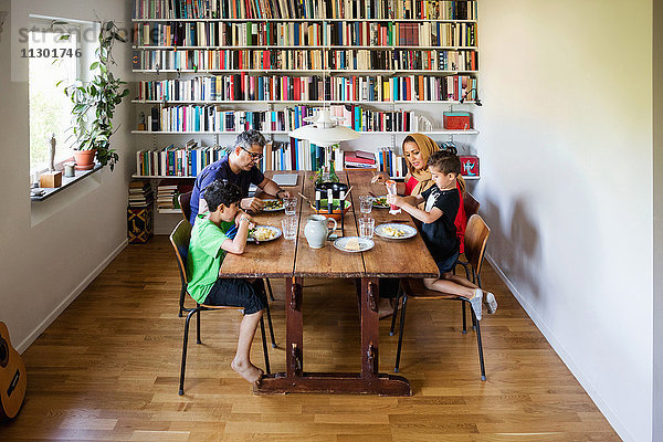 Familie beim Essen am Esstisch im Bücherregal