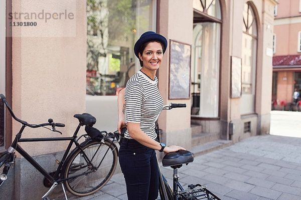 Seitenansicht Porträt einer glücklichen Frau mit Fahrrad auf dem Bürgersteig