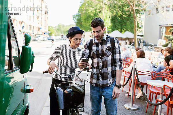 Paar mit Smartphone im Stehen am Bürgersteig Cafe