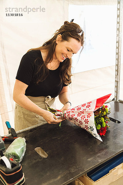 Fröhliche Arbeiterin beim Blumenstraußmachen am Marktstand