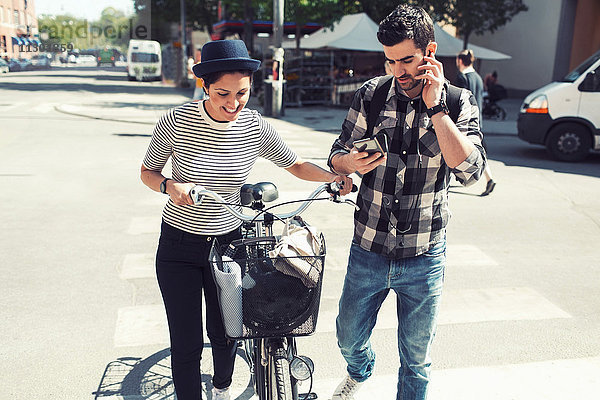 Mann mit Smartphone beim Gehen mit Frau auf der Straße
