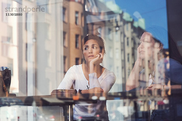 Nachdenkliche Frauen durch das Glasfenster im Café gesehen