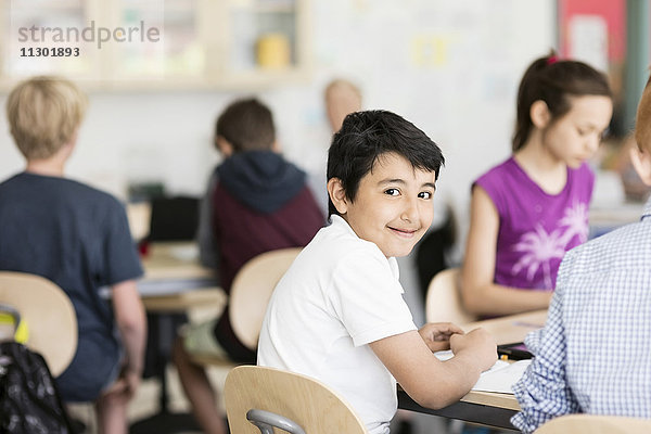 Porträt eines glücklichen Jungen mit Schülern im Klassenzimmer