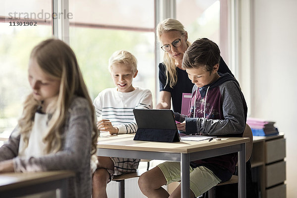 Lehrer unterstützt Kinder beim E-Learning mit digitalen Tabletts