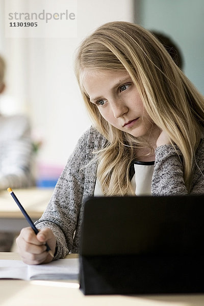 Nachdenkliches Mädchen am Schreibtisch im Klassenzimmer