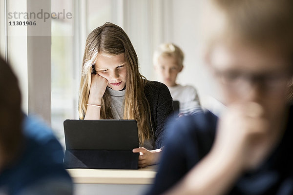 Mädchen lesen vom digitalen Tablett zum Lernen im Klassenzimmer