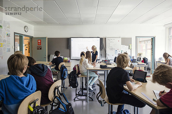 Lehrer erklärt den Schülern durch ein Whiteboard im Klassenzimmer
