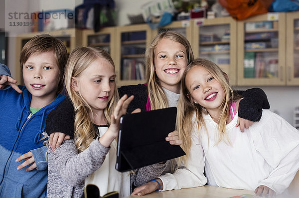Porträt von Freunden mit Mädchen mit Tablette im Klassenzimmer