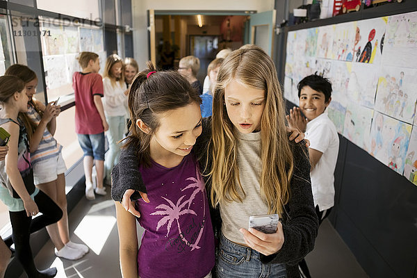 Mädchen per Handy mit Freunden im Flur der Schule