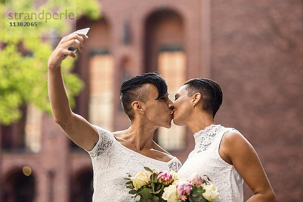 Lesbisches Paar nimmt Selfie vom Handy und küsst dabei