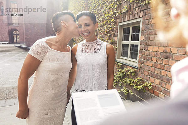 Lesbenpaar beim Küssen vor dem Priester während der Zeremonie