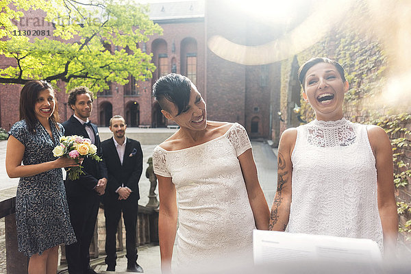 Fröhliches lesbisches Paar und Gast beim Lachen während der Zeremonie