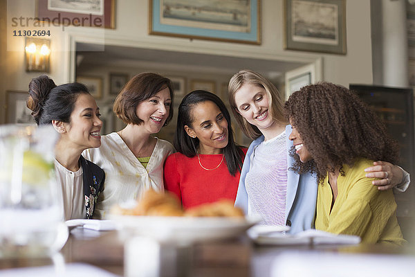 Lächelnde Frauen beim Essen und Reden im Restaurant