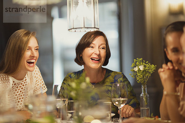 Lachende Frauenfreunde beim Essen und Reden am Restauranttisch