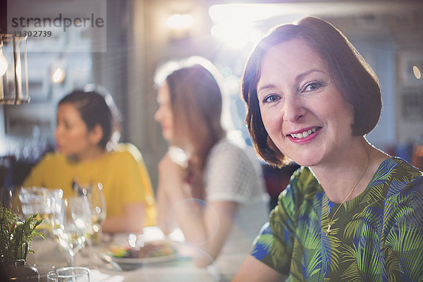 Portrait lächelnde Frau beim Essen mit Freunden am Restauranttisch