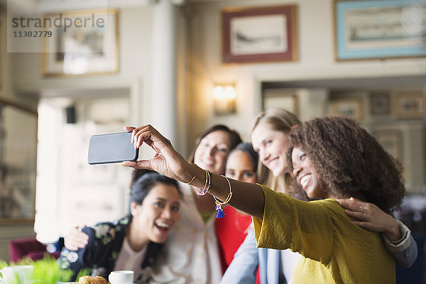 Lächelnde Frauenfreunde nehmen Selfie mit Fotohandy im Restaurant mit