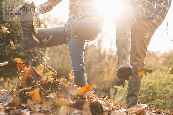 Paar in Regenstiefeln  die Herbstblätter treten