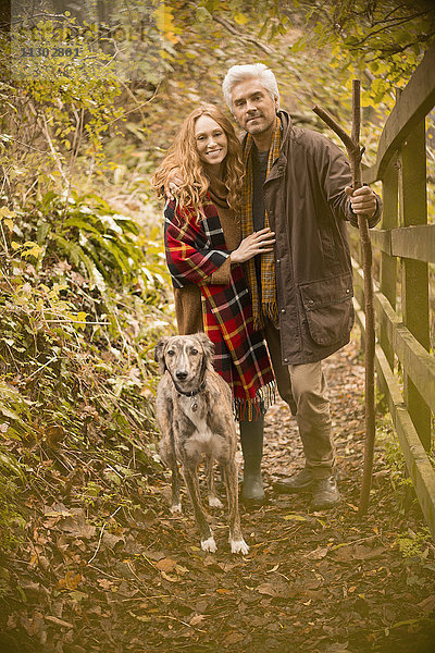 Porträt lächelnd Paar mit Hund und Spazierstock entlang Herbst Zaun