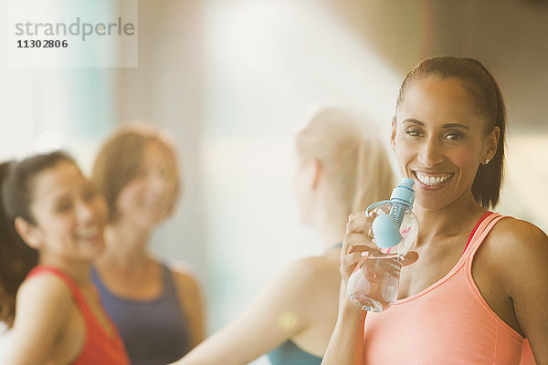 Portrait lächelnde Frau trinkt Wasser im Fitnessstudio der Übungsklasse