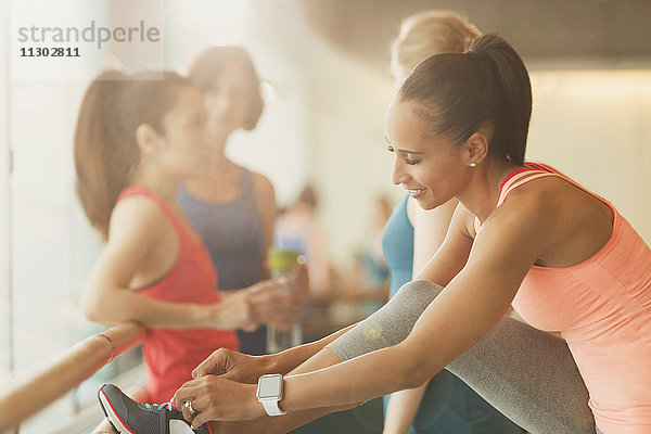 Frau beim Binden von Schuhen an der Stange im Fitness-Studio