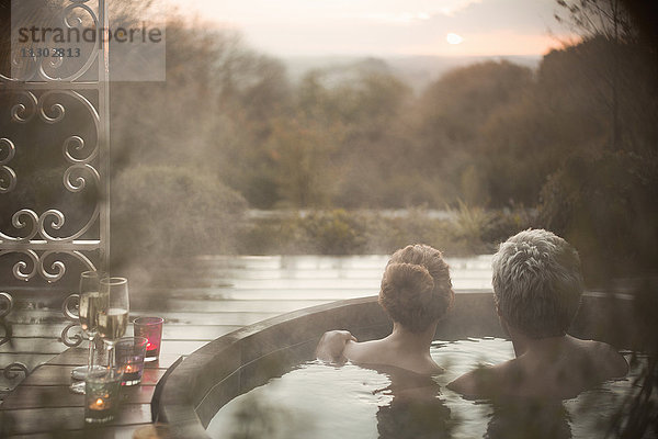 Gelassenes Paar im Whirlpool mit Blick auf den Herbstbaum