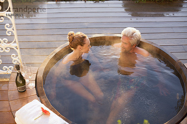 Ein Paar badet im Whirlpool und trinkt Champagner auf der Terrasse