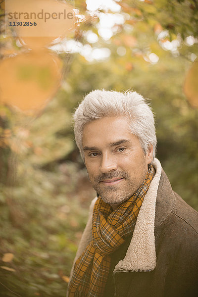 Porträt selbstbewusster Mann mit Schal im Herbstwald