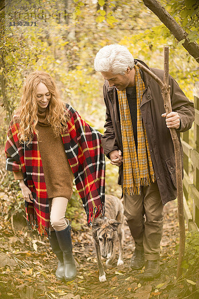 Ehepaar mit Hund und Spazierstock im Herbstwald