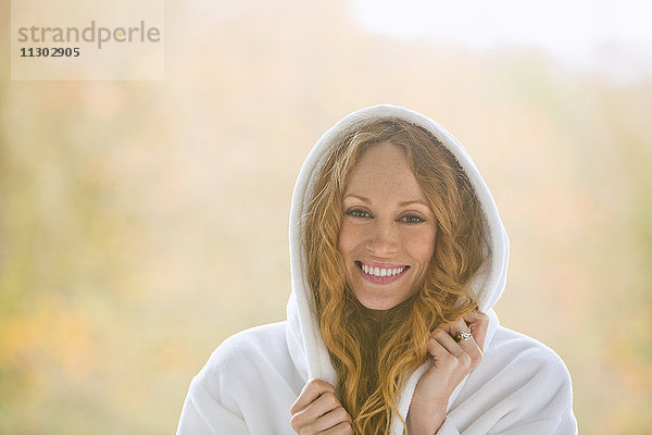 Porträt einer lächelnden Frau im Bademantel mit Kapuze