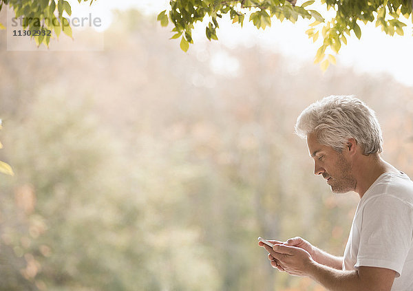 Mann schreibt SMS mit Handy auf Terrasse