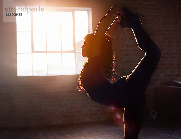 Silhouette Tänzerin Stretching praktizierende Yogakönigstänzerin Pose im Studio