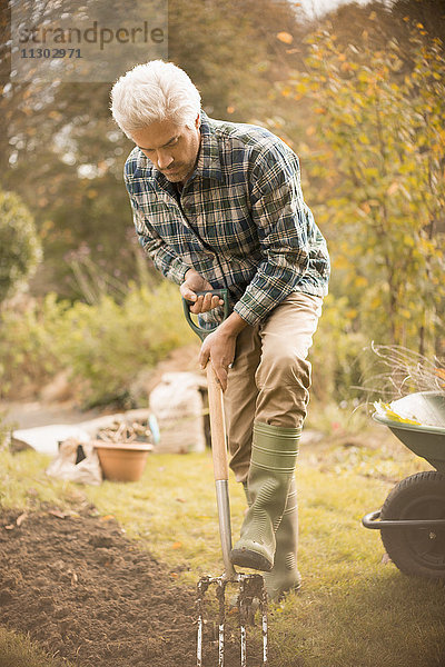 Mann bei der Gartenarbeit gräbt Erde im Herbstgarten