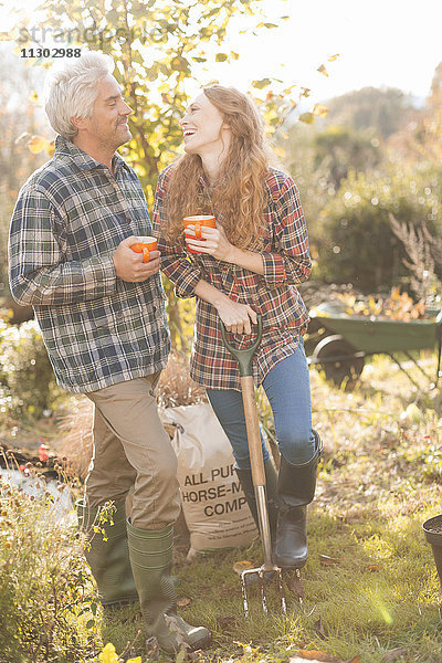Paar lachend genießen Kaffeepause Gartenarbeit sonnigen Herbst Garten