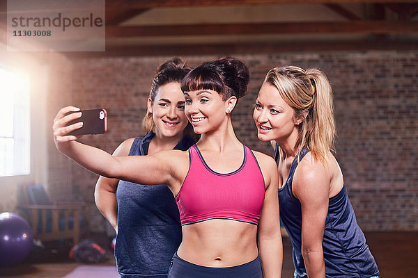 Fit junge Frauen in Sportbekleidung nehmen Selfie mit Kamera-Handy im Studio