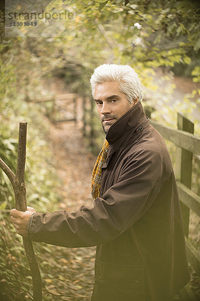Porträt ernster Mann mit Spazierstock auf Herbstweg