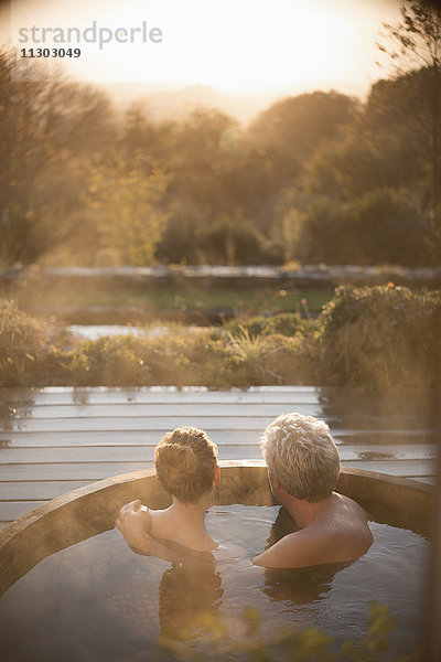 Gelassenes  liebevolles Paar  das im Whirlpool auf der Terrasse mit Blick auf den Herbst eintaucht