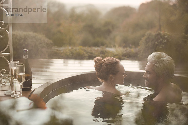 Pärchen im Gespräch im Whirlpool mit Champagner auf der Herbstterrasse