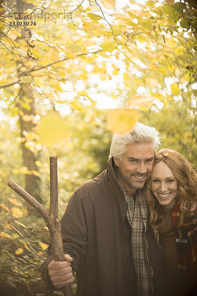 Portrait lächelndes Paar mit Spazierstock im Herbstwald